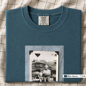 Blue Spruce colored folded t-shirt with a large vintage photo of a father and his son sitting on the bumper of an old car.