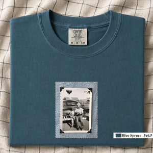 Blue Spruce colored folded t-shirt with a small vintage photo of a father and his son sitting on the bumper of an old car.