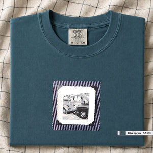 Blue spruce t-shirt with vintage photo of mechanics and cars on front of shirt.