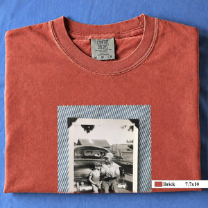 Brick colored folded t-shirt with a large vintage photo of a father and his son sitting on the bumper of an old car.