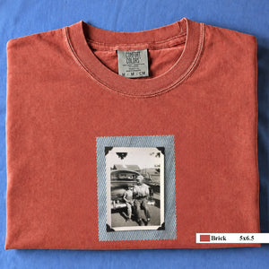 Brick colored folded t-shirt with a small vintage photo of a father and his son sitting on the bumper of an old car.