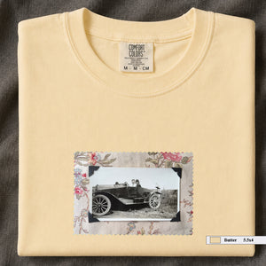 Butter colored folded t-shirt with small vintage snapshot of people riding in a 1920's car surrounded by a floral design.