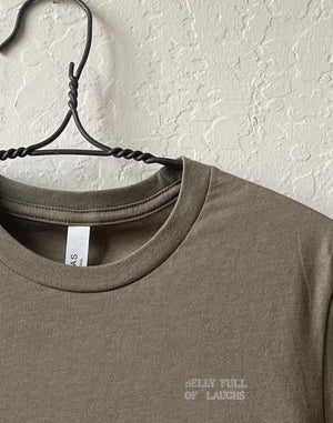 Close up shot of collage art t-shirt with tagline on front: 'Belly Full of Laughs' 