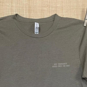 Close up shot of collage art t-shirt with tagline on front: 'His Thoughts Were Only On Her' 
