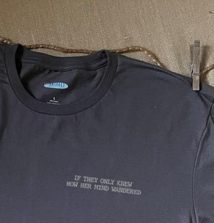 Close up shot of collage art t-shirt with tagline on front: 'If They Only Knew How Her Mind Wandered'
