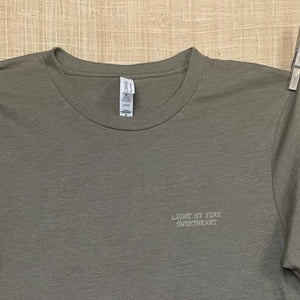 Close up shot of collage art t-shirt with tagline on front: 'Light My Fire Sweetheart'