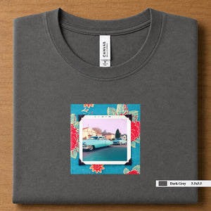 Dark Grey colored folded t-shirt with a vintage photo of two classic 50's cars on the street. Photo is surrounded by floral fabric.