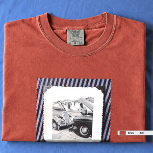Folded Brick or Orange t-shirt with a large vintage photo of mechanics and cars on front of shirt.