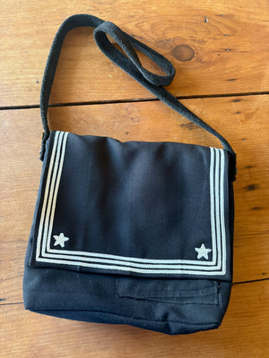 Front of a handmade bag made from navy uniform and suede straps.