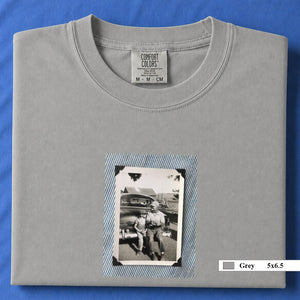 Grey colored folded t-shirt with a small vintage photo of a father and his son sitting on the bumper of an old car.