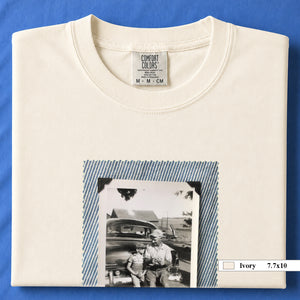 Ivory colored folded t-shirt with a large vintage photo of a father and his son sitting on the bumper of an old car.