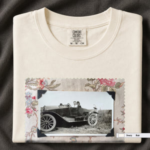 Ivory colored folded t-shirt with large vintage snapshot of people riding in a 1920's car surrounded by a floral design.