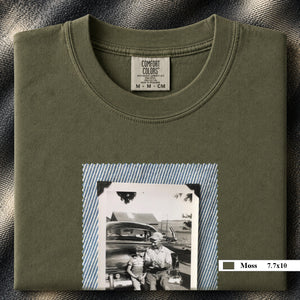 Moss colored folded t-shirt with a large vintage photo of a father and his son sitting on the bumper of an old car.