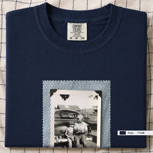 Navy colored folded t-shirt with a large vintage photo of a father and his son sitting on the bumper of an old car.