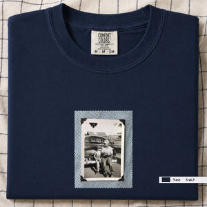 Navy colored folded t-shirt with a small vintage photo of a father and his son sitting on the bumper of an old car.