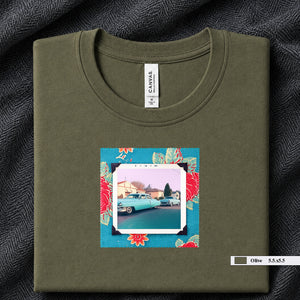 Olive colored folded t-shirt with a vintage photo of two classic 50's cars on the street. Photo is surrounded by floral fabric.