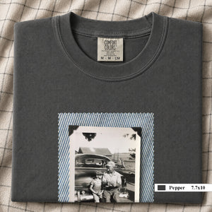 Pepper colored folded t-shirt with a large vintage photo of a father and his son sitting on the bumper of an old car.