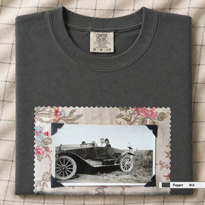 Pepper colored folded t-shirt with large vintage snapshot of people riding in a 1920's car surrounded by a floral design.