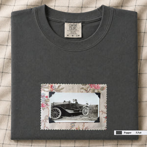 Pepper colored folded t-shirt with small vintage snapshot of people riding in a 1920's car surrounded by a floral design.