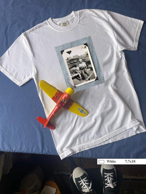 White t-shirt with large vintage photo of a boy and his son sitting on the bumper of an old car.