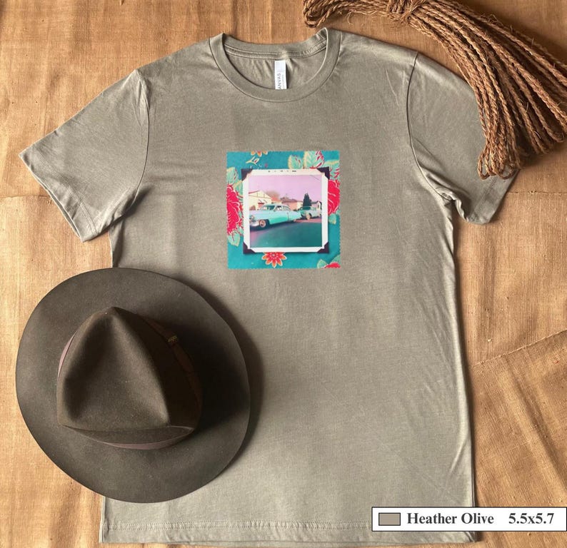 A hat and  t-shirt with a patch on the front of a vintage photo of two classic 50's cars .