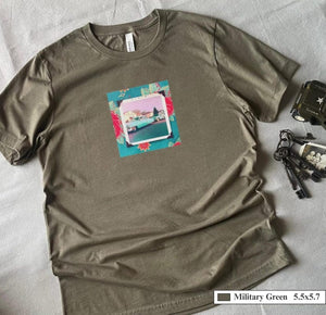 A t-shirt with a patch on the front of a vintage photo of two classic 50's cars framed in a floral fabric.