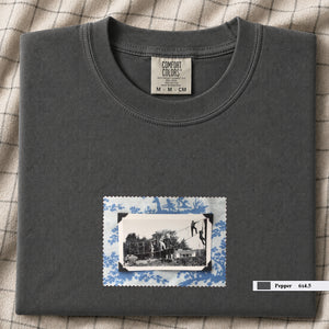 Charcoal colored folded tshirt with small vintage photo of kids playing in trees on front of shirt