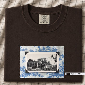 dark brown colored folded tshirt with large vintage photo of kids playing in trees on front of shirt