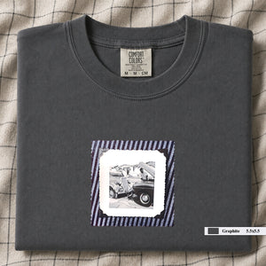 Graphite colored folded t-shirt with vintage photo of mechanics and cars on front of shirt.