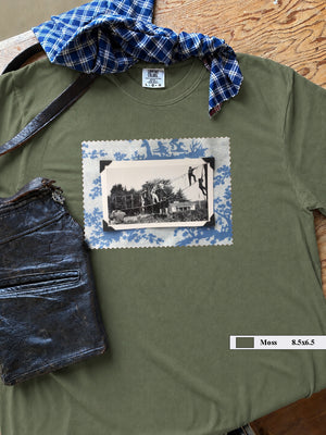 Olive  t-shirt on table with large vintage photo of kids playing on front.