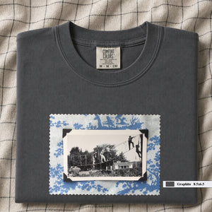 Grey colored folded tshirt with large vintage photo of kids playing in trees on front of shirt