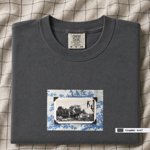 Grey colored folded tshirt with small vintage photo of kids playing in trees on front of shirt