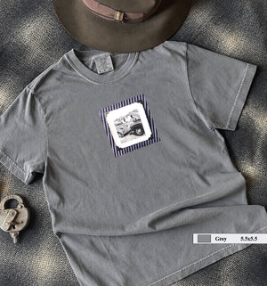 grey t-shirt on table with small vintage photo of mechanics and cars on front of shirt.