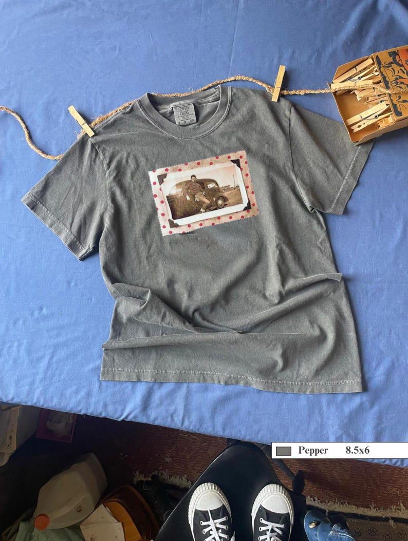 A grey t-shirt with a polka dot framed vintage photo of a boy and his holster in front of an old car