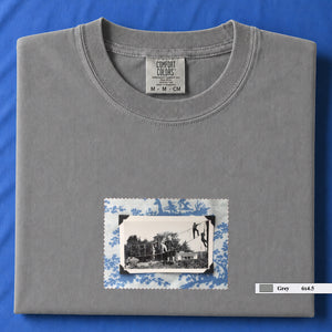 Light grey colored folded tshirt with small vintage photo of kids playing in trees on front of shirt