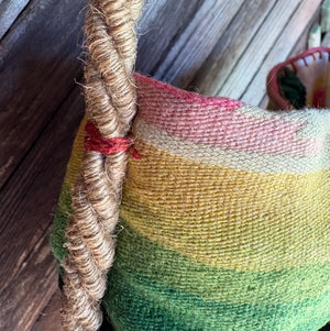 Handle detail of a handmade basket shoulder bag with a Mexican blanket textile and natural fiber floral detail.