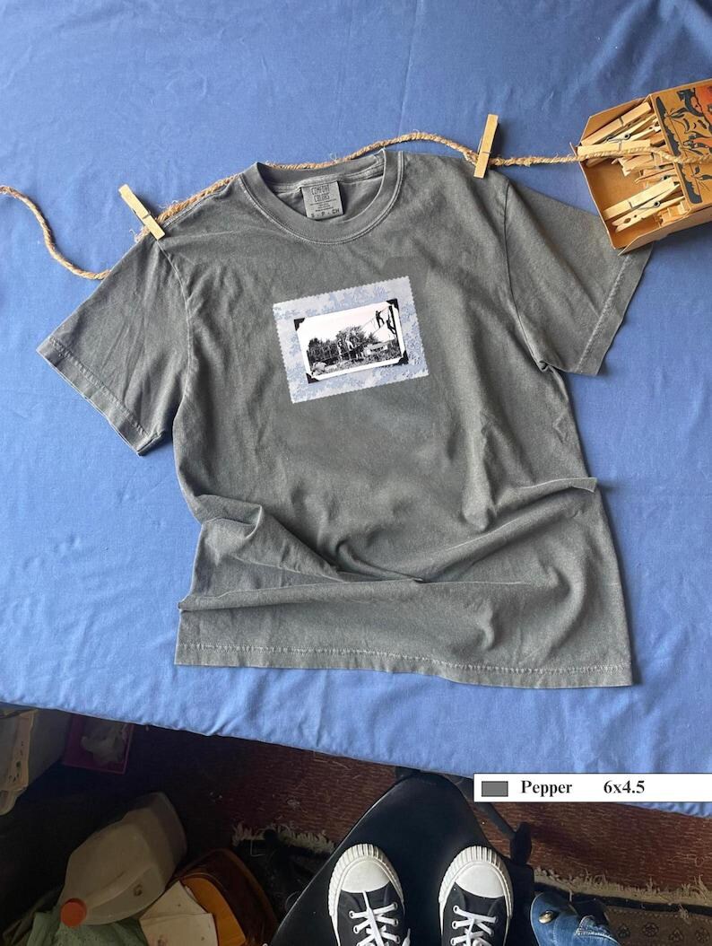 T-shirt front of vintage photo of kids playing on suspended rope ladders in the trees.