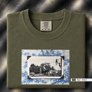 Olive colored folded tshirt with large vintage photo of kids playing in trees on front of shirt