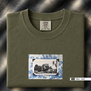 Olive colored folded tshirt with small vintage photo of kids playing in trees on front of shirt