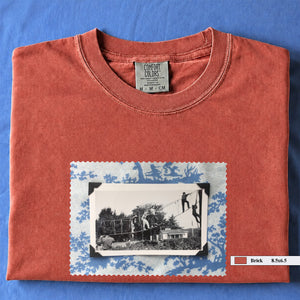 Orange colored folded tshirt with large vintage photo of kids playing in trees on front of shirt