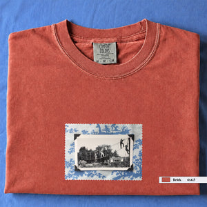 Orange colored folded tshirt with small vintage photo of kids playing in trees on front of shirt